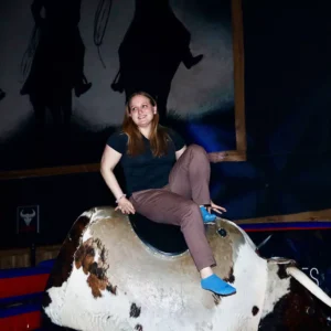 Guest smiling while riding the mechanical bull at Imagen Venues, a turn-key corporate event venue in Houston
