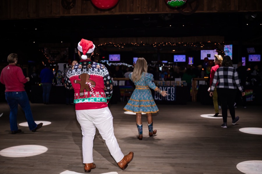 Line dancing on the lit dance floor at a Houston company holiday party