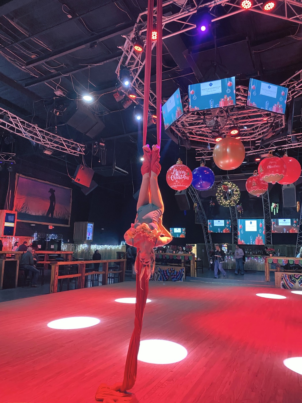 Aerial silks performer above the dance floor with giant ornaments at a Stampede Event Center holiday party