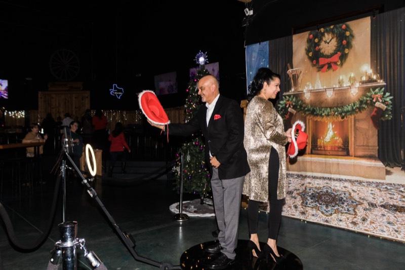 Couple at the 360 photo booth with a holiday fireplace backdrop