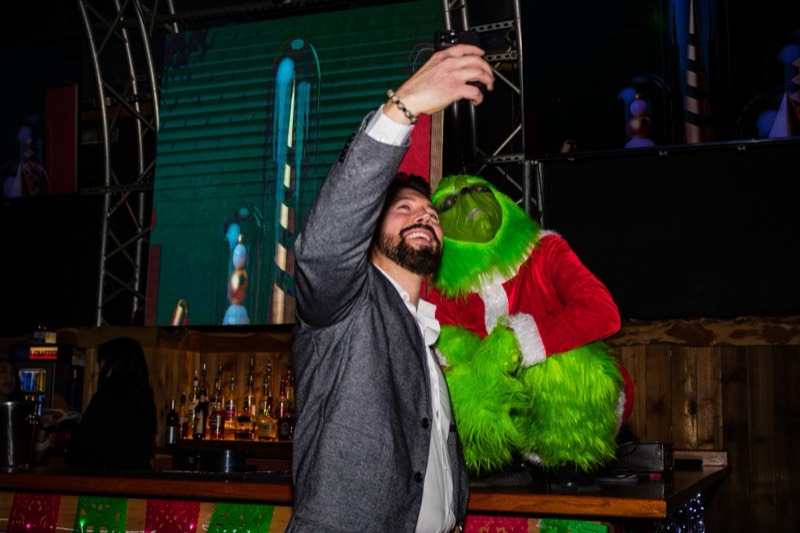 Guest taking a selfie with the Grinch at a company holiday party